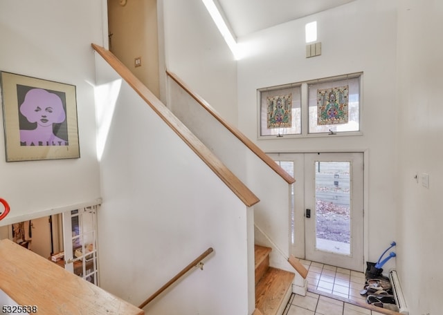 stairs featuring tile patterned floors, a towering ceiling, and french doors