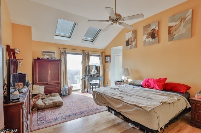 bedroom with access to outside, ceiling fan, light hardwood / wood-style flooring, and lofted ceiling with skylight