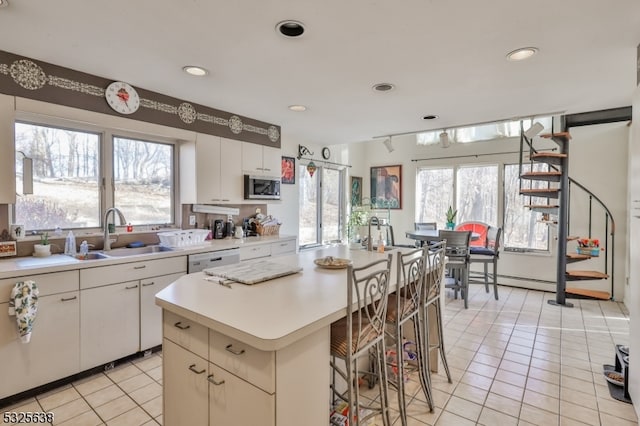 kitchen with white cabinets, a kitchen island, plenty of natural light, and sink