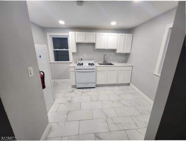 kitchen featuring white cabinetry, white range with gas stovetop, and sink