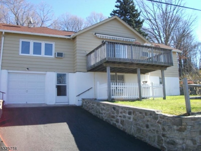 back of house featuring a garage and a wooden deck