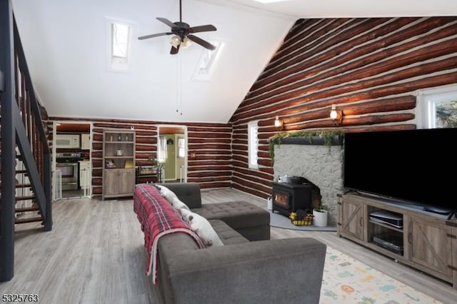 living area featuring stairs, ceiling fan, wood finished floors, and a wood stove