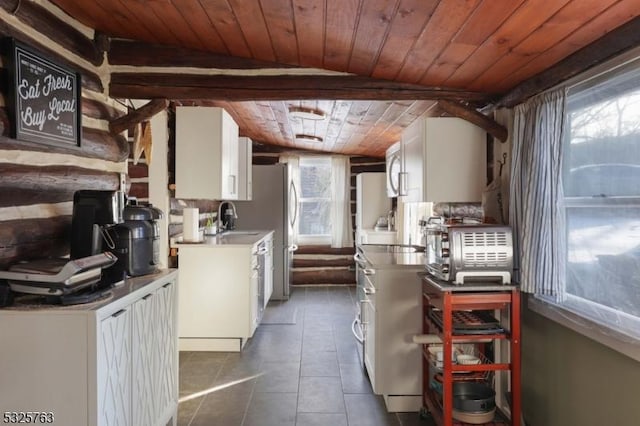 kitchen with a toaster, white cabinets, a sink, dark tile patterned flooring, and wooden ceiling