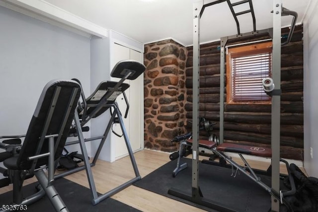 exercise room featuring rustic walls and wood finished floors