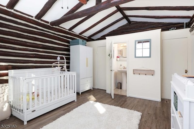 bedroom with lofted ceiling with beams, dark wood-style flooring, a sink, and ensuite bath