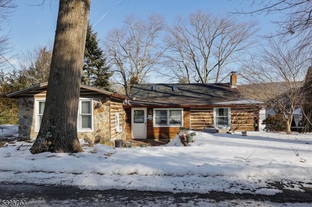 cabin featuring stone siding and a chimney