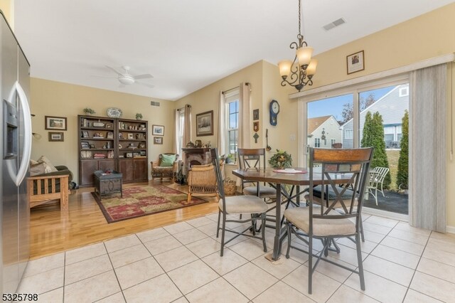 dining room with ceiling fan with notable chandelier and light hardwood / wood-style flooring