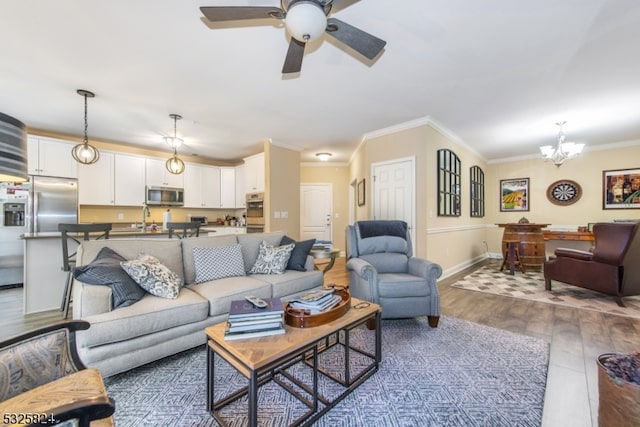 living room featuring crown molding, dark hardwood / wood-style flooring, ceiling fan with notable chandelier, and sink