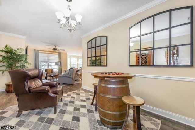 living area with crown molding, ceiling fan with notable chandelier, and hardwood / wood-style flooring