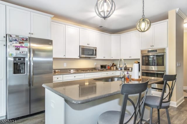 kitchen with sink, stainless steel appliances, dark hardwood / wood-style floors, and a kitchen island with sink