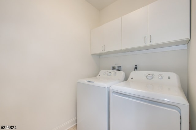 laundry room with washing machine and clothes dryer and cabinets