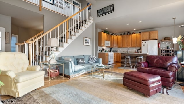 living room featuring a towering ceiling, light hardwood / wood-style flooring, and sink