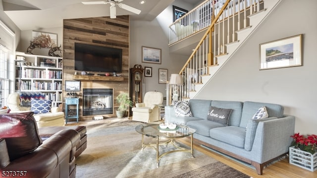 living room featuring hardwood / wood-style floors, ceiling fan, a fireplace, and high vaulted ceiling