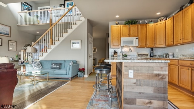 kitchen with decorative backsplash, white appliances, and light hardwood / wood-style flooring