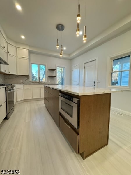 kitchen featuring white cabinets, a kitchen island, hanging light fixtures, and stainless steel appliances