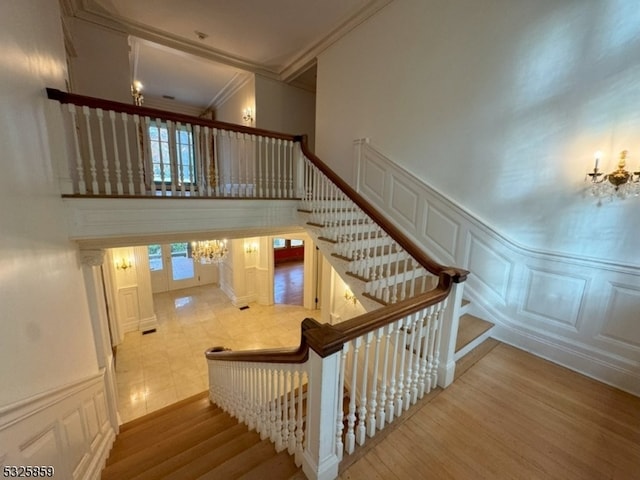 stairway with crown molding, french doors, and wood-type flooring