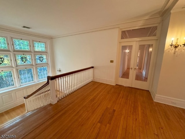 empty room featuring french doors, ornamental molding, and wood-type flooring