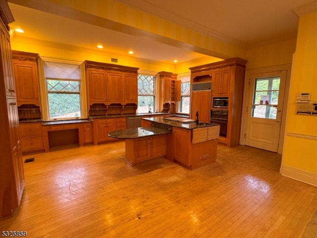 kitchen with stainless steel appliances, light hardwood / wood-style flooring, dark stone counters, a kitchen island, and ornamental molding