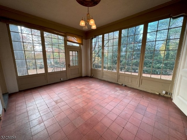 unfurnished sunroom featuring a healthy amount of sunlight and a notable chandelier