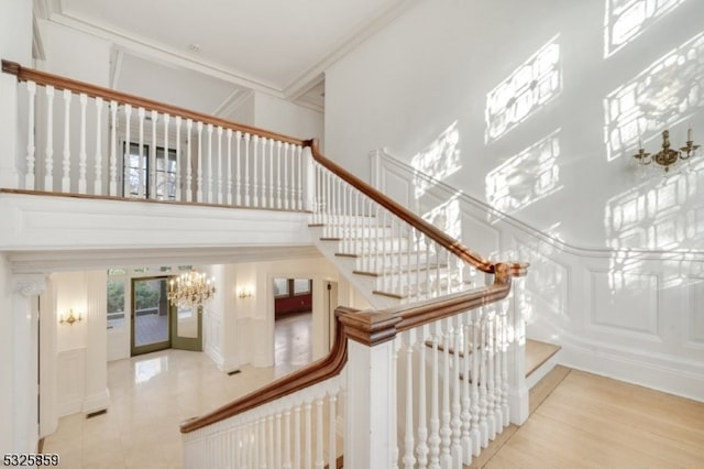 stairway with wood-type flooring, crown molding, and a high ceiling