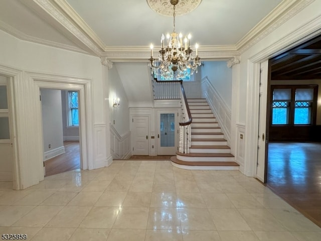 foyer entrance with a notable chandelier, light wood-type flooring, and ornamental molding