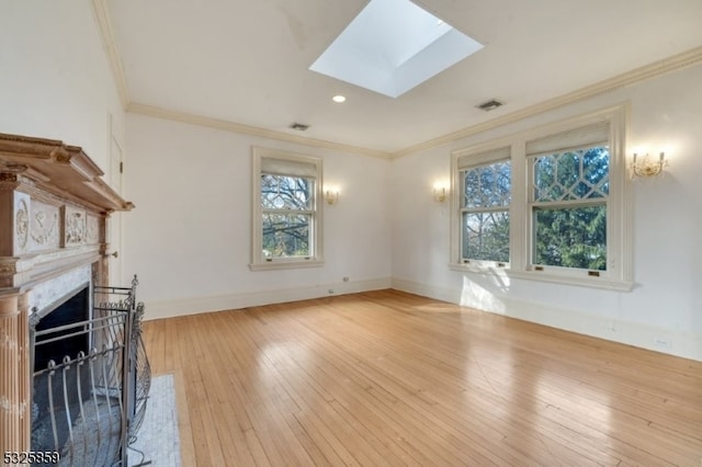 unfurnished living room featuring light wood-type flooring, a skylight, and ornamental molding