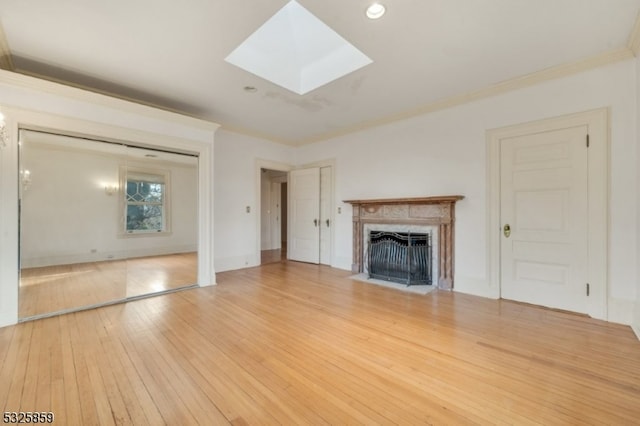 unfurnished living room with a skylight, hardwood / wood-style flooring, and ornamental molding