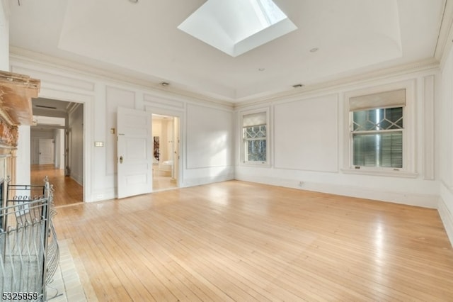 spare room with a skylight, light hardwood / wood-style flooring, and a tray ceiling