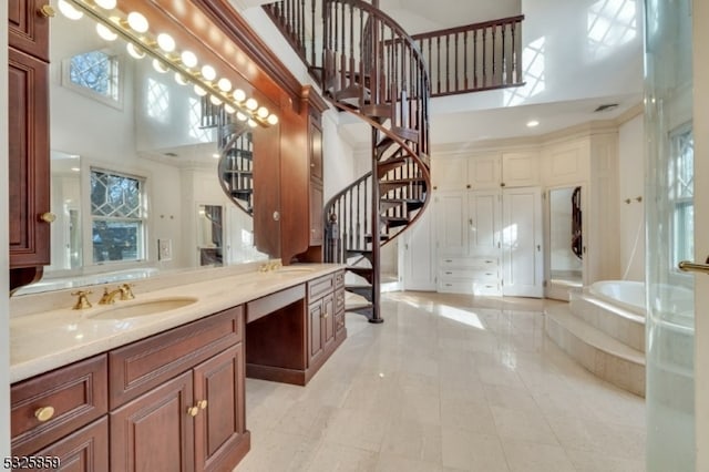 bathroom featuring vanity, a wealth of natural light, a relaxing tiled tub, and a high ceiling