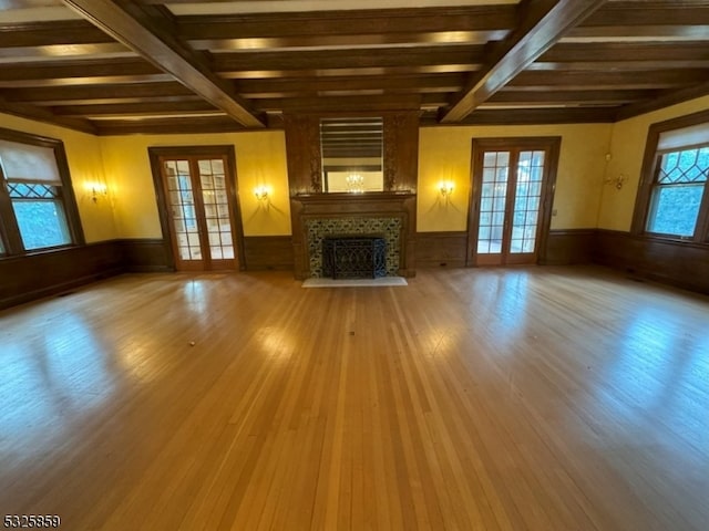 unfurnished living room with hardwood / wood-style floors, beamed ceiling, and french doors