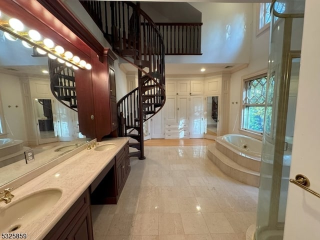 bathroom with tile patterned flooring, a high ceiling, vanity, and tiled bath