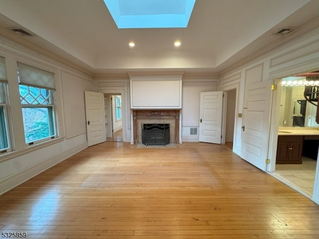 unfurnished living room featuring a skylight and light hardwood / wood-style floors