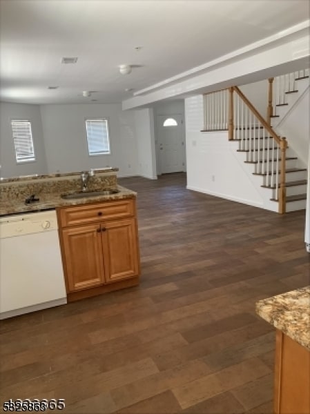 kitchen featuring light stone countertops, white dishwasher, dark wood-type flooring, and sink