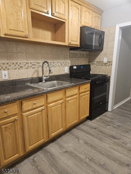 kitchen with dark hardwood / wood-style flooring, tasteful backsplash, sink, black appliances, and dark stone countertops