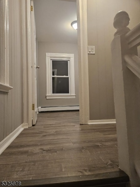 hall featuring dark hardwood / wood-style flooring, baseboard heating, and wood walls