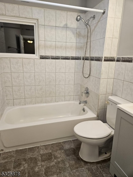 full bathroom featuring vanity, toilet, tile walls, and tiled shower / bath combo