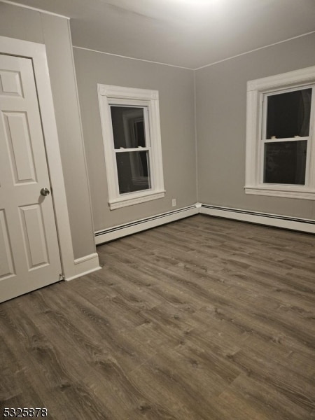 spare room with dark hardwood / wood-style flooring and a baseboard heating unit