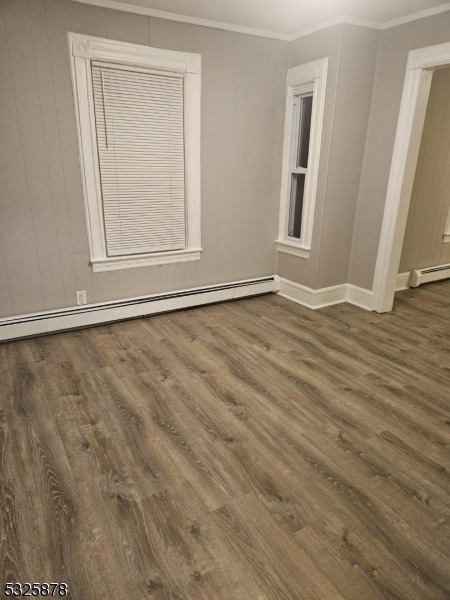 unfurnished room with crown molding, dark wood-type flooring, and a baseboard heating unit