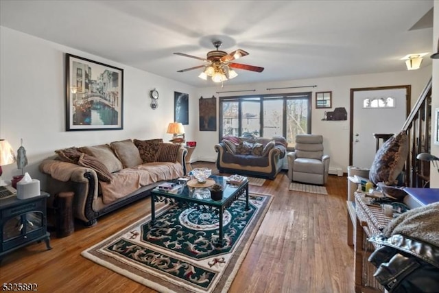 living room featuring ceiling fan, wood-type flooring, and a wood stove