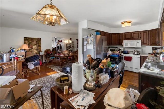 kitchen featuring dark brown cabinets, decorative light fixtures, wood-type flooring, and white appliances