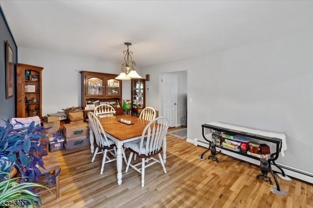 dining space with light hardwood / wood-style flooring and a baseboard heating unit