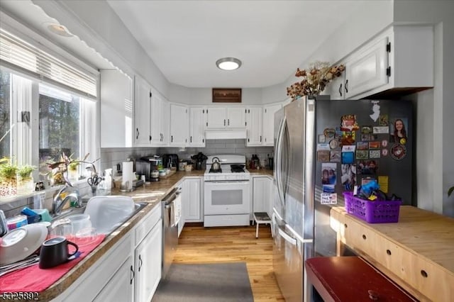 kitchen featuring decorative backsplash, white cabinetry, appliances with stainless steel finishes, and light hardwood / wood-style flooring