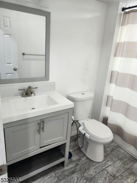 bathroom featuring vanity, curtained shower, and toilet