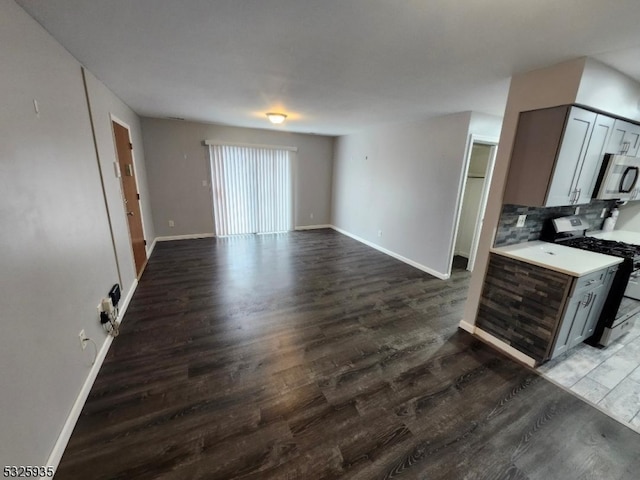 kitchen featuring dark hardwood / wood-style flooring, white range oven, gray cabinets, and tasteful backsplash