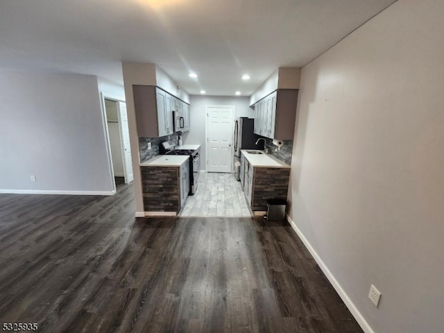 kitchen featuring hardwood / wood-style flooring, sink, stainless steel appliances, and tasteful backsplash