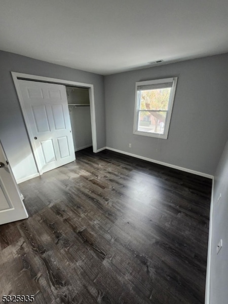 unfurnished bedroom with dark hardwood / wood-style flooring and a closet