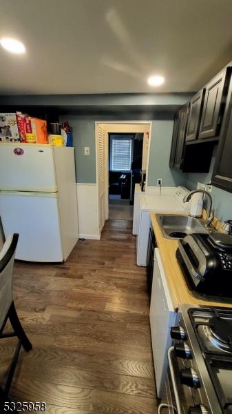 kitchen featuring sink, stainless steel stove, dark hardwood / wood-style floors, butcher block countertops, and white fridge