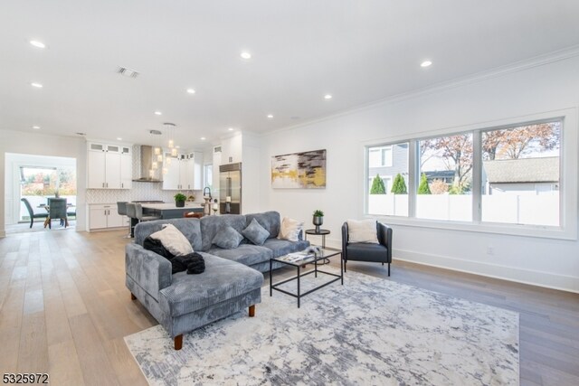 living room with light hardwood / wood-style flooring, a wealth of natural light, and ornamental molding