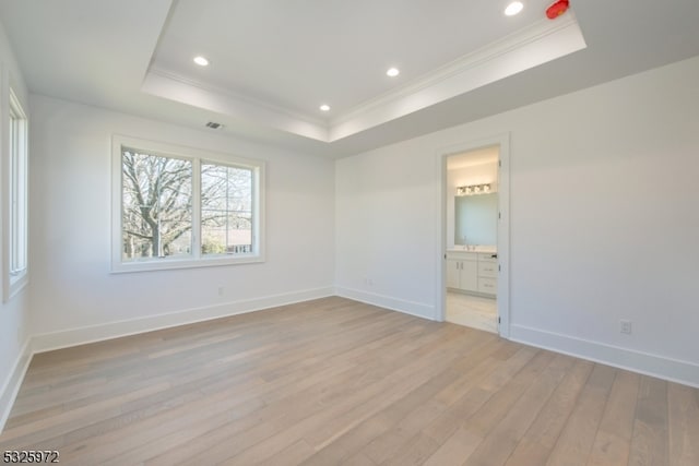 unfurnished room with crown molding, a raised ceiling, and light hardwood / wood-style flooring