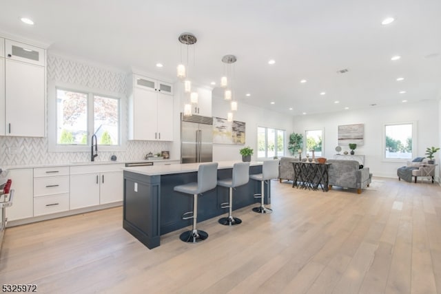 kitchen featuring stainless steel built in refrigerator, a center island, hanging light fixtures, and white cabinets